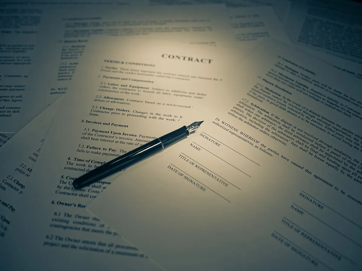Een contract met handtekeningregels ligt op een bureau met een vulpen erop.